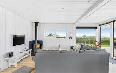a living room with a gray couch and a tv at Awesome Home In Øster Assels With Sauna in Øster Assels