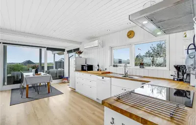 a kitchen with white cabinets and a table and some windows at Awesome Home In Øster Assels With Sauna in Øster Assels