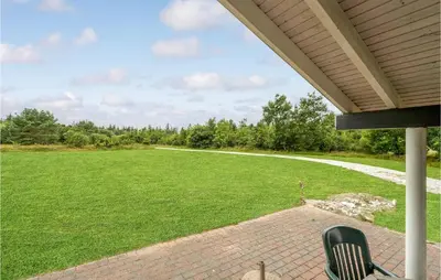 a porch with a chair and a field of grass at 3 Bedroom Beautiful Home In Frøstrup in Frøstrup