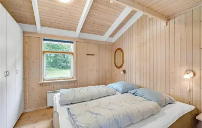 a large bed in a room with wooden walls at 3 Bedroom Beautiful Home In Frøstrup in Frøstrup
