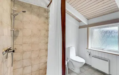a bathroom with a toilet and a shower and a window at 3 Bedroom Beautiful Home In Frøstrup in Frøstrup