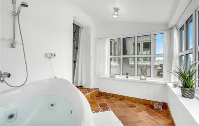 a white bathroom with a tub and a window at Beautiful Home In Frøstrup With Sauna in Frøstrup