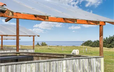 a horse grazing in a field with a wooden fence at Stunning Home In Hanstholm With Kitchen in Hanstholm