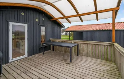 a wooden deck with a black table on it at Stunning Home In Hanstholm With Kitchen in Hanstholm
