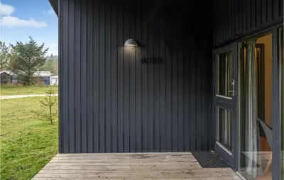 a black house with a wooden porch with a door at Stunning Home In Hanstholm With Kitchen in Hanstholm