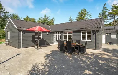 a house with a table and a red umbrella at 4 Bedroom Amazing Home In Hurup Thy in Sønder Ydby