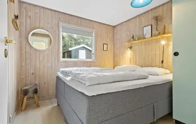 a bed in a room with a wooden wall at 2 Bedroom Awesome Home In Farsø in Farsø