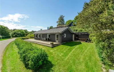 a small house on a lawn next to a road at Cozy Home In Farsø With Sauna in Farsø