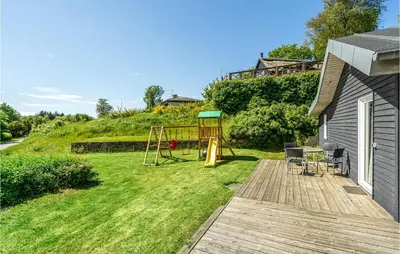a backyard with a wooden deck with a playground at Cozy Home In Farsø With Sauna in Farsø