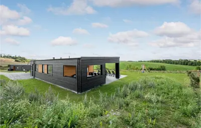 a black house in a field with grass at 4 Bedroom Stunning Home In Løgstrup in Løgstrup