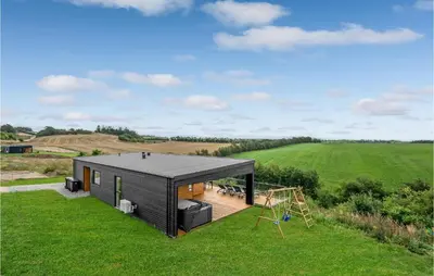 a black house in a field with a playground at Beautiful Home In Løgstrup With Kitchen in Løgstrup