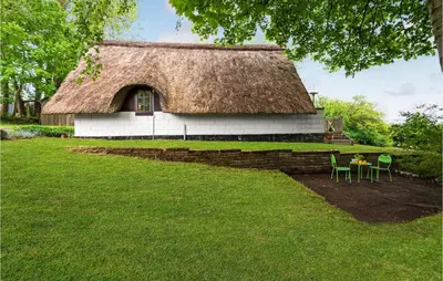 a house with a thatched roof with a table and chairs at Beautiful Home In Løgstrup With Wifi in Løgstrup