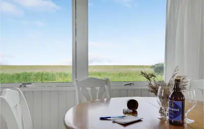 a table with a bottle and chairs and a window at 1 Bedroom Beautiful Home In Løgstør in Løgstør