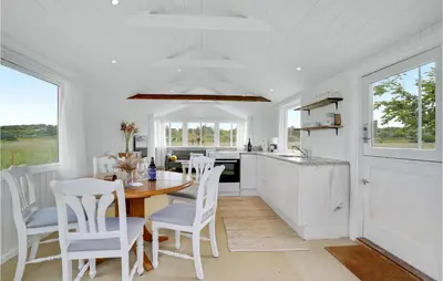 a white kitchen with a wooden table and chairs at 1 Bedroom Beautiful Home In Løgstør in Løgstør