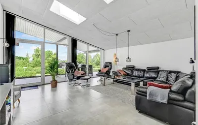 a living room with black leather furniture and windows at Cozy Home In Farsø With Wifi in Farsø