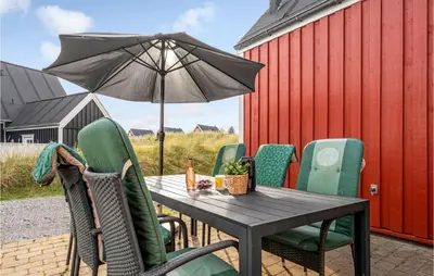 a table and chairs with an umbrella on a patio at Amazing Home In Blokhus With Wifi in Blokhus