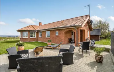 a brick house with a patio with chairs and tables at Awesome Home In Lemvig With Kitchen in Lemvig