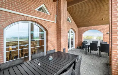 an outdoor patio with a wooden table and chairs at Awesome Home In Lemvig With Kitchen in Lemvig