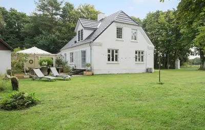 a white house with a yard with chairs and an umbrella at Pet Friendly Home In Roslev With Wifi in Roslev