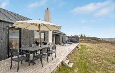 a wooden deck with a table and an umbrella at 3 Bedroom Stunning Home In Thyholm in Thyholm