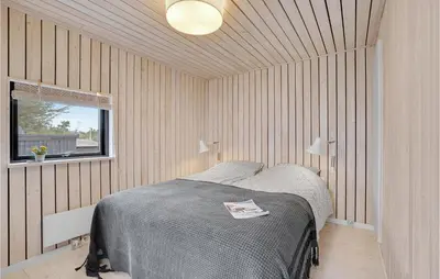 a bedroom with a bed in a room with wooden walls at 3 Bedroom Stunning Home In Thyholm in Thyholm