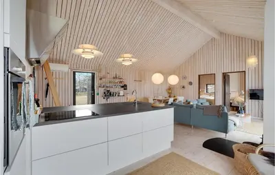 a kitchen with white cabinets and a living room at 3 Bedroom Stunning Home In Thyholm in Thyholm