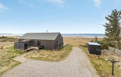 a small shack in a field with a tree at 3 Bedroom Stunning Home In Thyholm in Thyholm