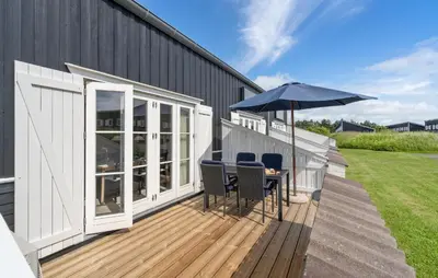 a deck with a table and an umbrella at Agger Havn Feriecenter in Vestervig
