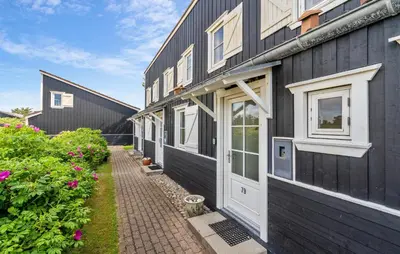a row of houses with white doors and flowers at Agger Havn Feriecenter in Vestervig