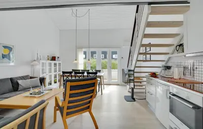 a kitchen and living room with a spiral staircase at Agger Havn Feriecenter in Vestervig