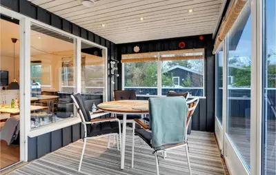 a screened in porch with a wooden table and chairs at Cozy Home In Pandrup With Kitchen in Pandrup