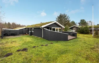 a black house with a turf roof on a yard at Cozy Home In Pandrup With Kitchen in Pandrup