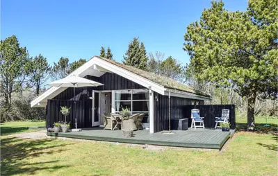 a black shed with a deck and an umbrella at 3 Bedroom Amazing Home In Pandrup in Pandrup