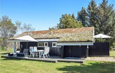 a house with a deck with chairs and umbrellas at 3 Bedroom Amazing Home In Pandrup in Pandrup