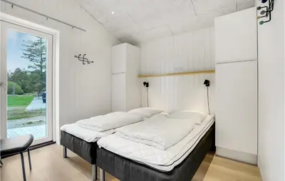a bed in a room with a large window at Amazing Home In Blokhus With Sauna in Blokhus