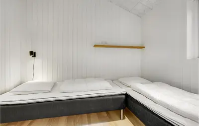 two beds in a small room with white walls at Amazing Home In Blokhus With Sauna in Blokhus