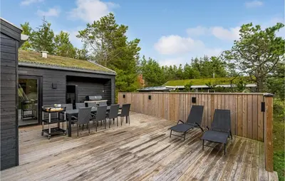 a wooden deck with chairs and a table on it at Amazing Home In Blokhus With Sauna in Blokhus