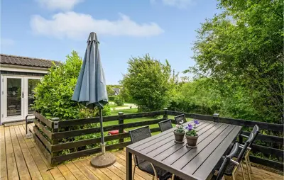 a wooden table with an umbrella on a deck at Cozy Home In Roslev With Wifi in Roslev