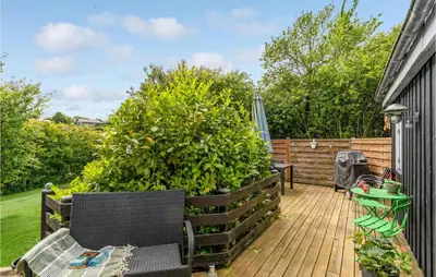 a wooden deck with a bench and a large bush at Cozy Home In Roslev With Wifi in Roslev