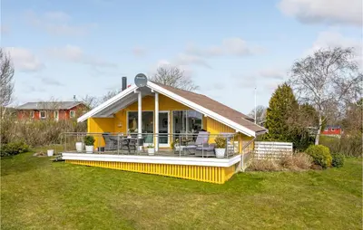 a yellow house with a large deck on a yard at Lovely Home In Roslev With Kitchen in Roslev