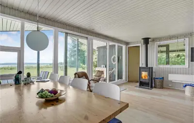 a dining room with a table and a fireplace at Lovely Home In Spøttrup in Spottrup