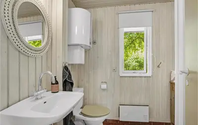 a bathroom with a sink and a toilet and a mirror at Lovely Home In Spøttrup in Spottrup
