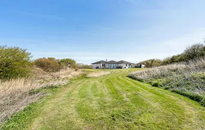a field of grass with a house in the background at Stunning Home In Vestervig With Sauna in Vestervig