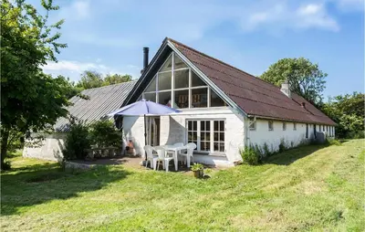 a white house with a table and an umbrella at Cozy Home In Nykøbing M With Kitchen in Tæbring