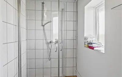 a shower in a bathroom with white tiles at Cozy Home In Nykøbing M With Kitchen in Tæbring