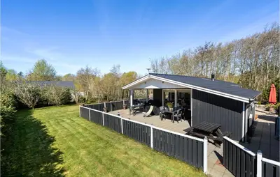 a small house with a deck and a backyard at 4 Bedroom Stunning Home In Thyholm in Thyholm