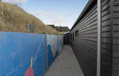 a side walk with a blue wall and a building at Cozy Home In Blokhus With Kitchen in Blokhus