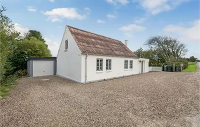 a white building with a garage on a gravel driveway at 1 Bedroom Beautiful Home In Roslev in Roslev