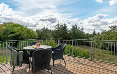 a table and chairs on a wooden deck at Lovely Home In Aabybro With Kitchen in Åbybro