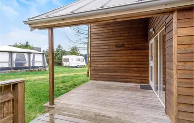 a wooden cabin with a deck and a building at Lovely Home In Hanstholm With Wifi in Hanstholm